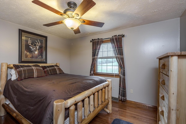 bedroom featuring a textured ceiling, ceiling fan, wood finished floors, and baseboards