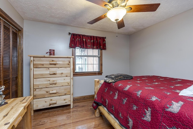 bedroom featuring a closet, a textured ceiling, a ceiling fan, and wood finished floors