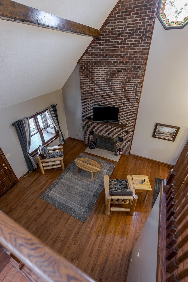 living room with vaulted ceiling with beams, a fireplace with flush hearth, and wood finished floors