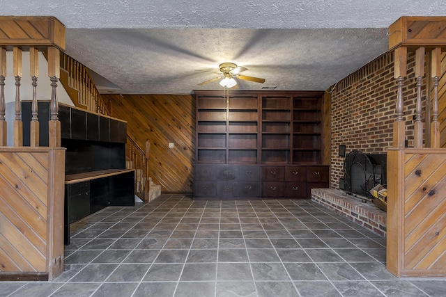 unfurnished living room featuring a textured ceiling, a brick fireplace, built in features, and wooden walls