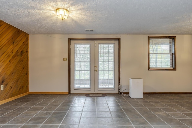 doorway with french doors, wood walls, and plenty of natural light