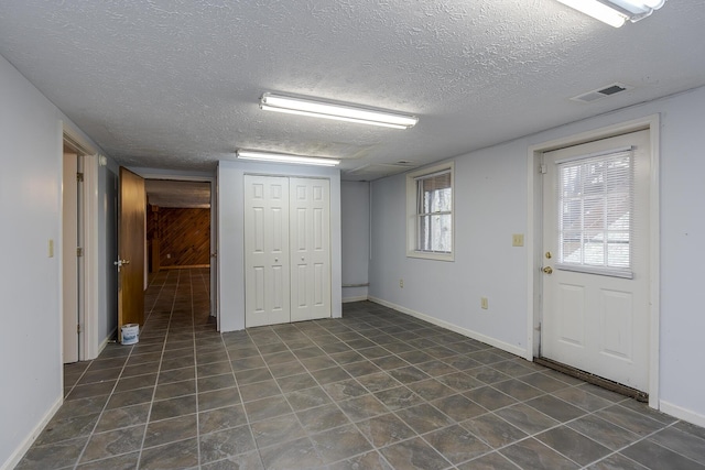 interior space with baseboards, visible vents, and a textured ceiling