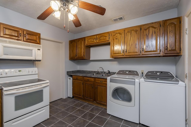 interior space featuring white appliances, visible vents, independent washer and dryer, dark tile patterned floors, and a sink