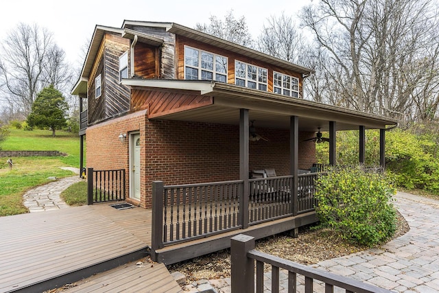 exterior space with a deck, a ceiling fan, and brick siding