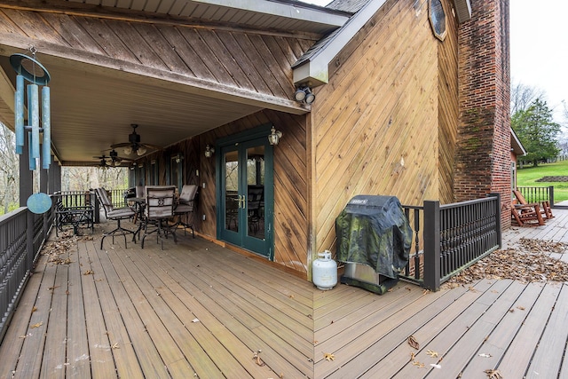 deck with french doors, outdoor dining space, a grill, and a ceiling fan