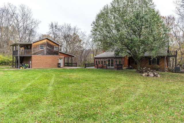 view of yard with central AC, a balcony, and a sunroom