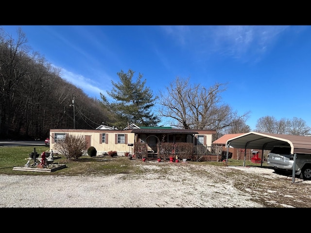 manufactured / mobile home with a detached carport, covered porch, and driveway