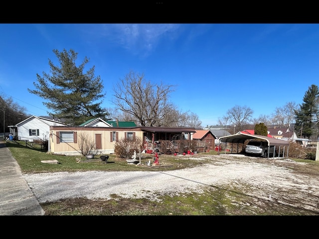 view of front facade featuring a carport, covered porch, a front yard, and driveway