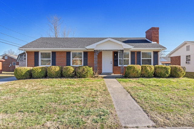 single story home featuring brick siding, a chimney, a front yard, and a shingled roof