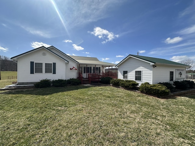 back of property featuring metal roof and a lawn