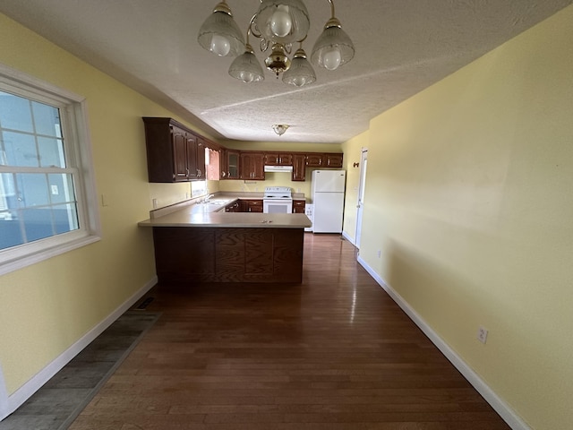 kitchen featuring white appliances, baseboards, dark wood-style floors, a peninsula, and a textured ceiling