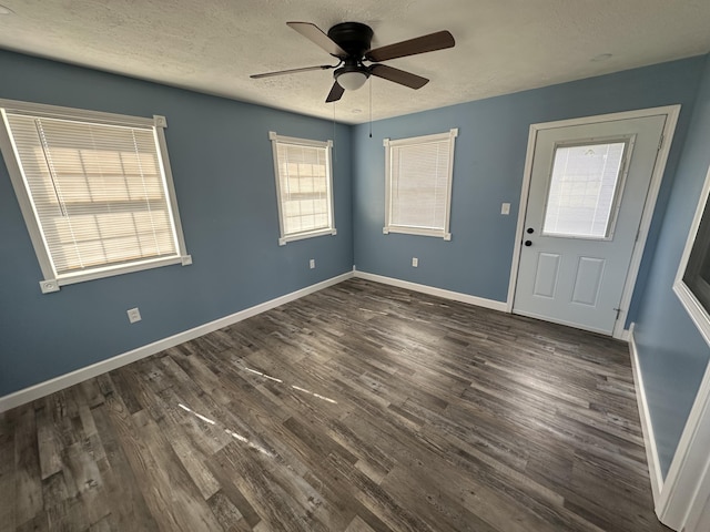 spare room with a ceiling fan, dark wood finished floors, a textured ceiling, and baseboards