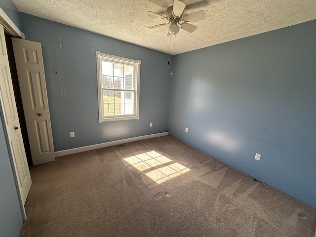 unfurnished room with carpet floors, a ceiling fan, visible vents, and a textured ceiling