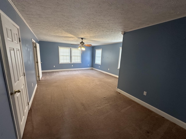 carpeted empty room with a ceiling fan, crown molding, a textured ceiling, and baseboards