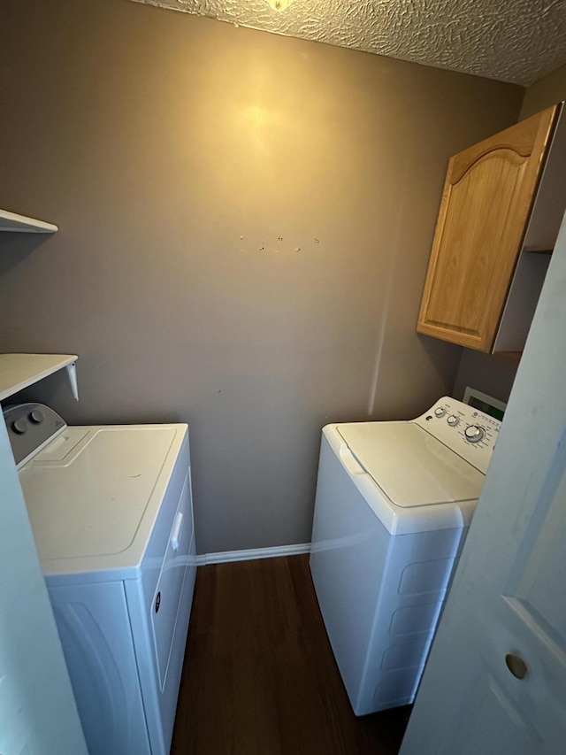 laundry area featuring cabinet space, baseboards, dark wood-style flooring, a textured ceiling, and washer and dryer