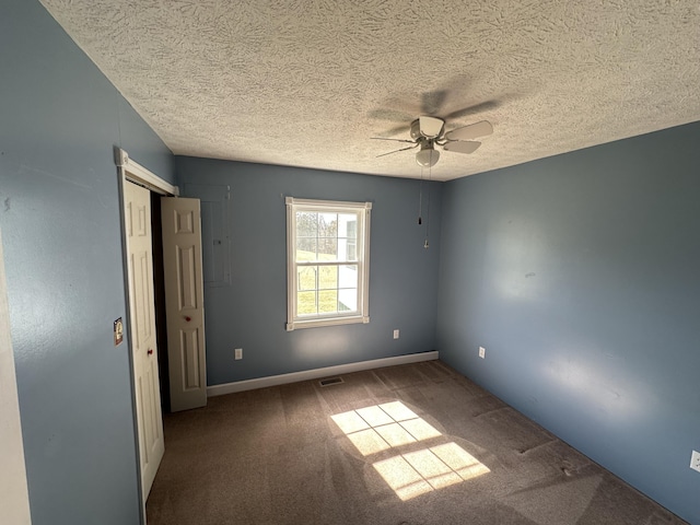 spare room with carpet, visible vents, ceiling fan, a textured ceiling, and baseboards