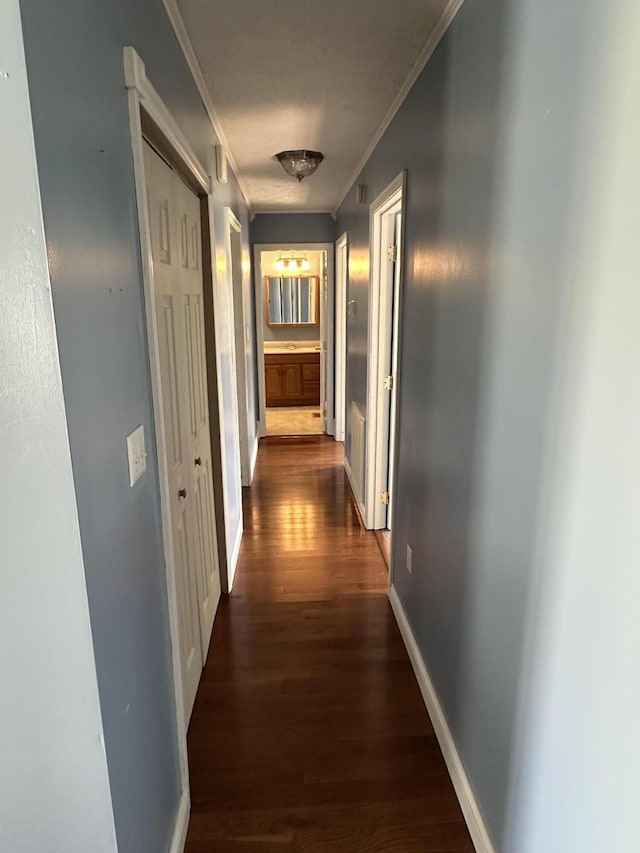 corridor featuring ornamental molding, dark wood finished floors, and baseboards