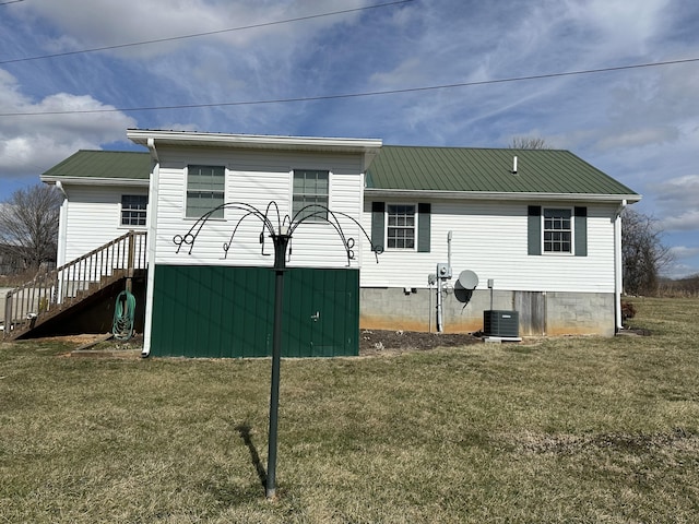 rear view of property featuring cooling unit, metal roof, and a lawn