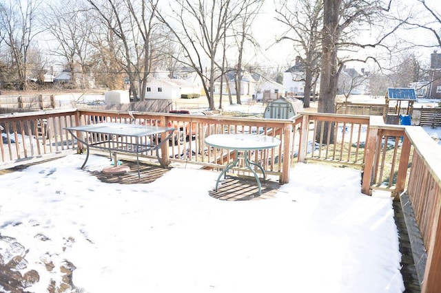 snow covered deck with an outbuilding, a storage shed, and fence