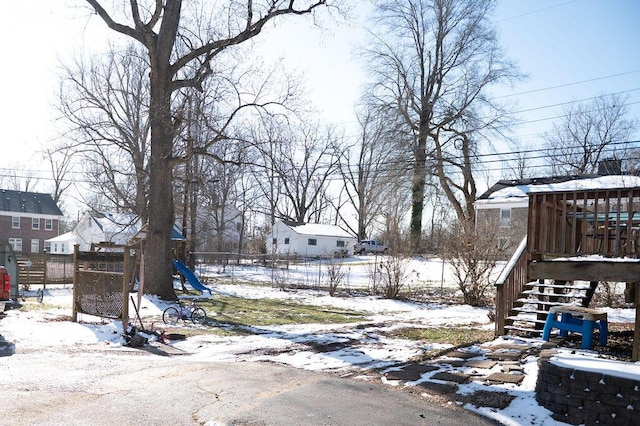 yard covered in snow with a playground and fence