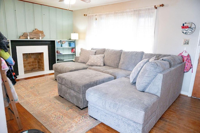 living room with a fireplace with flush hearth, ceiling fan, and wood finished floors