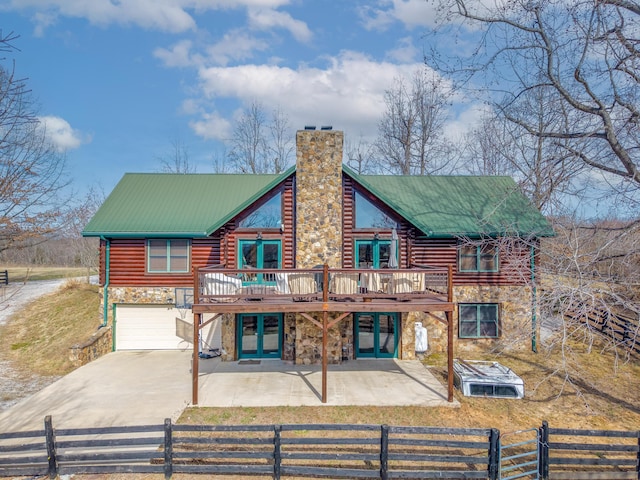 view of front of house featuring stone siding, a fenced front yard, a chimney, metal roof, and french doors