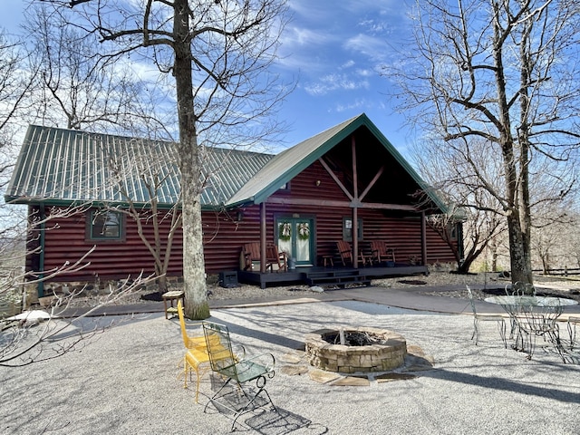 rear view of house featuring an outdoor fire pit, a patio area, and metal roof