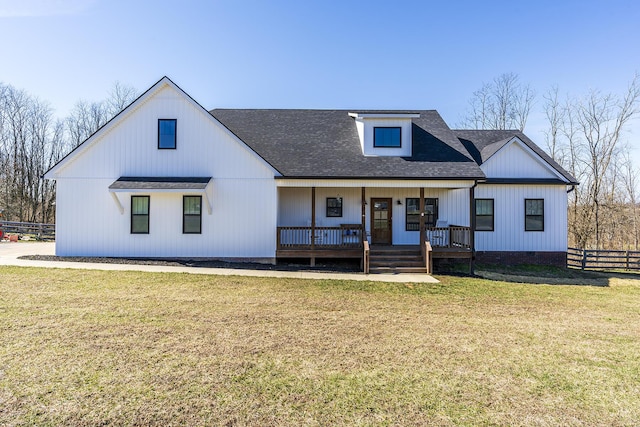 modern inspired farmhouse with a front yard, a porch, fence, and a shingled roof