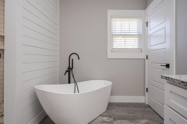 bathroom featuring vanity, a soaking tub, and baseboards