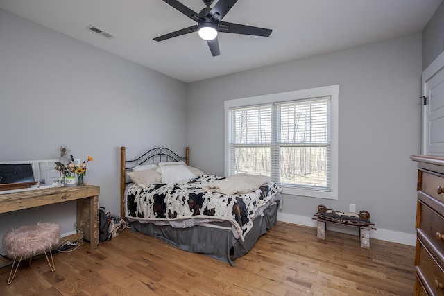 bedroom featuring ceiling fan, visible vents, baseboards, and wood finished floors