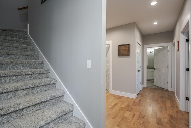 stairway featuring recessed lighting, wood finished floors, and baseboards