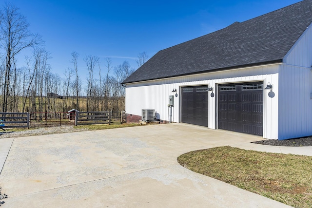 detached garage featuring central AC unit and fence
