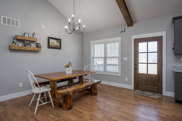 dining area with visible vents, wood finished floors, an inviting chandelier, baseboards, and vaulted ceiling with beams