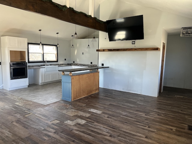 kitchen with wall oven, dark wood-style floors, vaulted ceiling with beams, and a sink