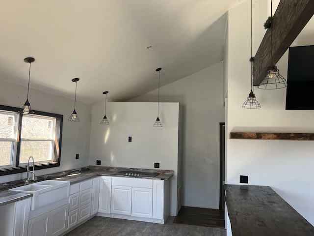 kitchen with dark countertops, lofted ceiling, white cabinetry, a sink, and black electric cooktop