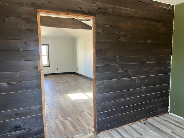 unfurnished room with wooden walls, baseboards, and wood finished floors