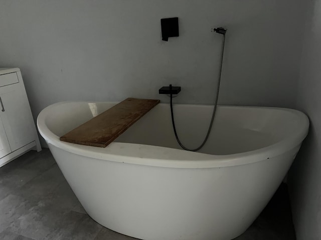 details with washer / clothes dryer, a freestanding tub, and unfinished concrete flooring