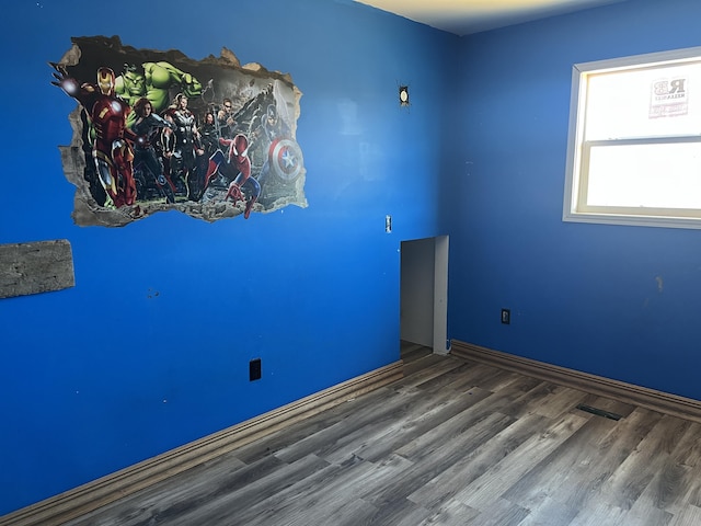 empty room featuring baseboards, visible vents, and wood finished floors