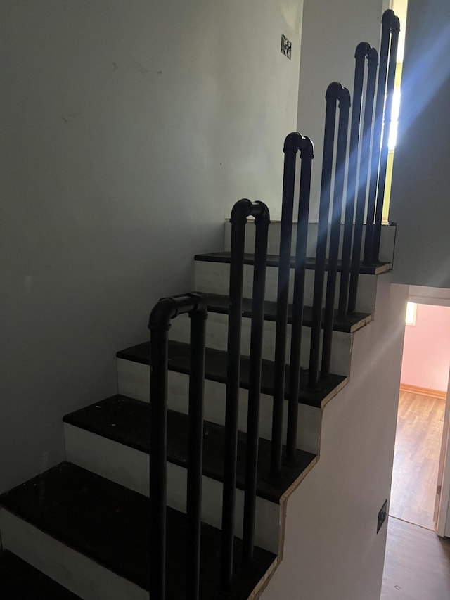 stairway featuring wood finished floors and a healthy amount of sunlight