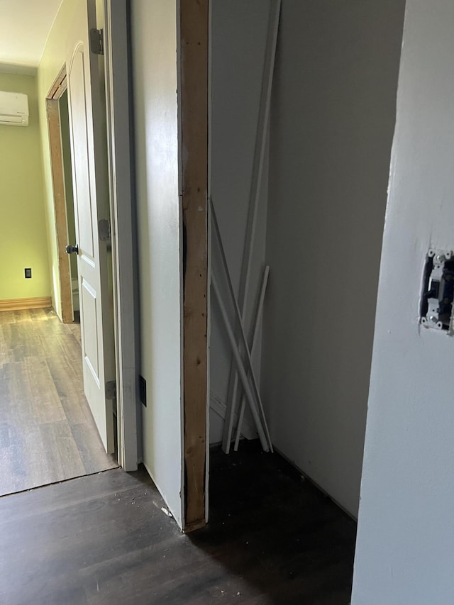 hallway with an AC wall unit and wood finished floors