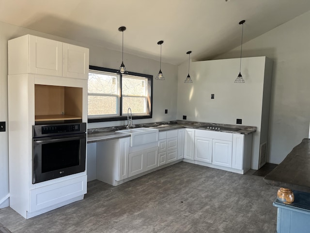 kitchen with dark countertops, oven, a sink, and lofted ceiling