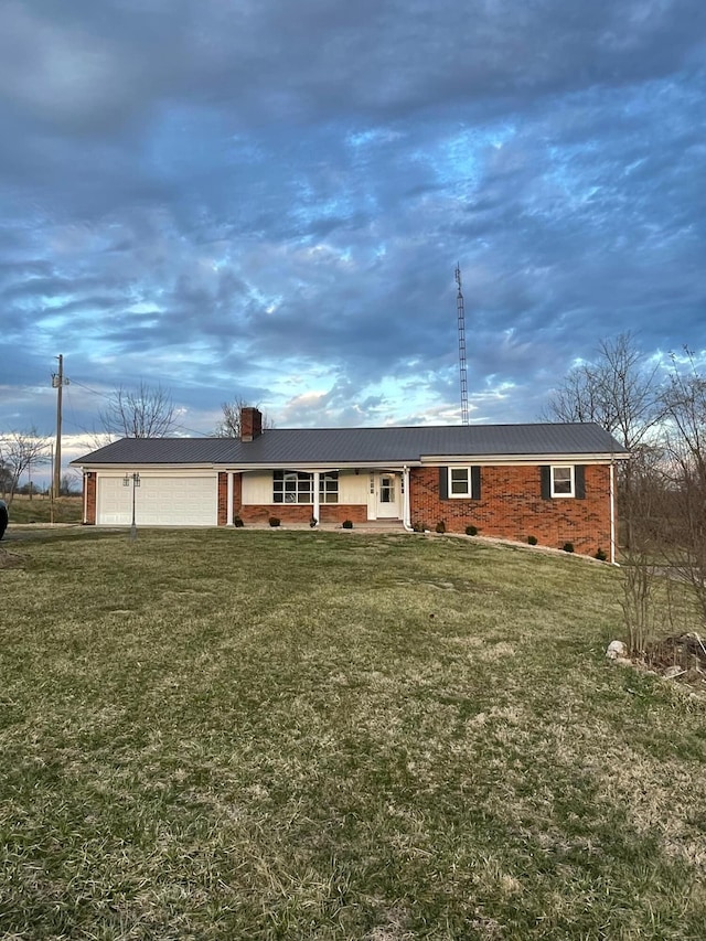 view of front of home with a garage, brick siding, a chimney, and a front lawn