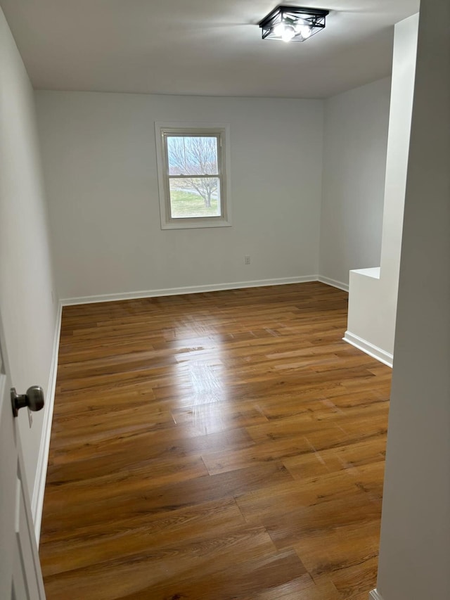 unfurnished room with baseboards and wood finished floors