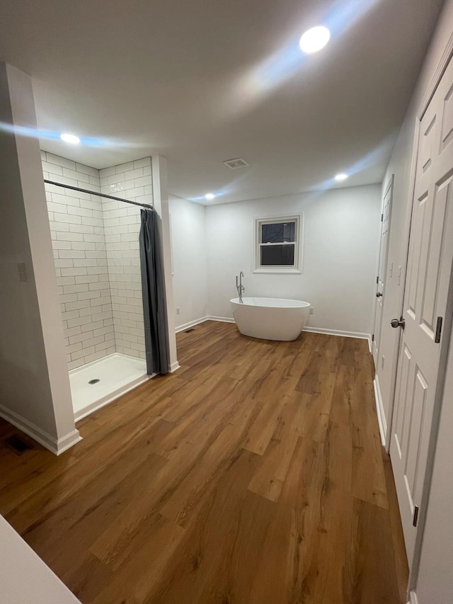 full bathroom with wood finished floors, visible vents, baseboards, a freestanding bath, and a stall shower