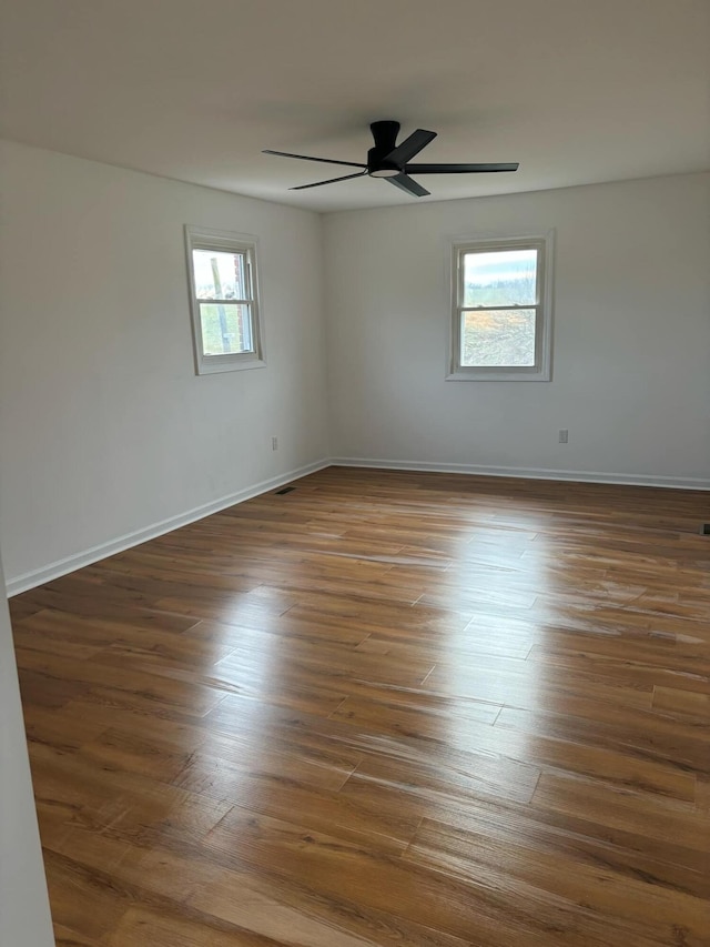 spare room featuring ceiling fan, baseboards, and dark wood-type flooring