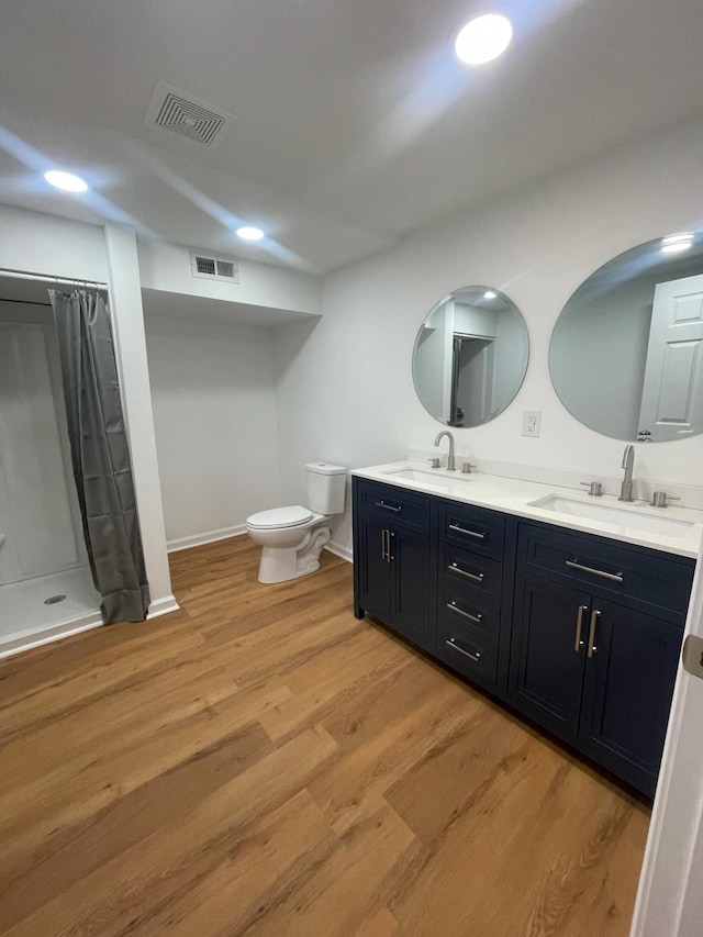 bathroom with wood finished floors, a sink, and visible vents