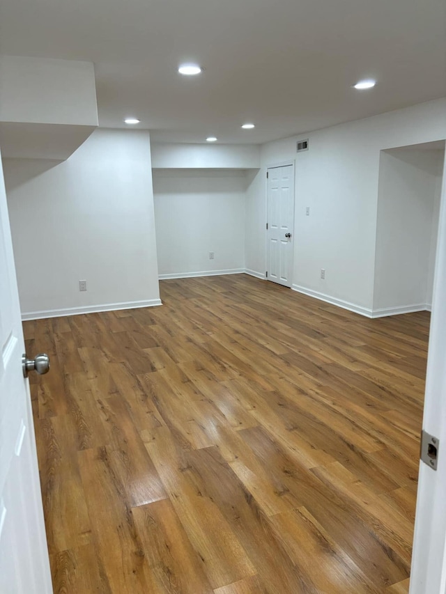 finished below grade area with recessed lighting, visible vents, baseboards, and wood finished floors