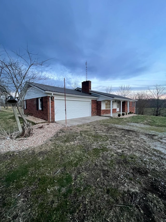 view of front of house with a garage, driveway, brick siding, and a chimney