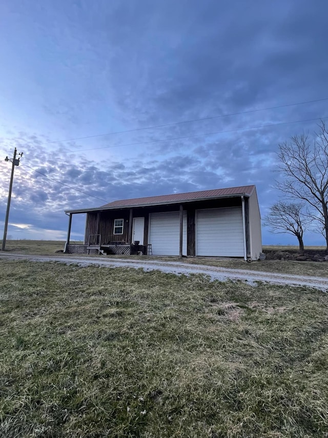 exterior space with a garage, metal roof, an outdoor structure, and a front yard