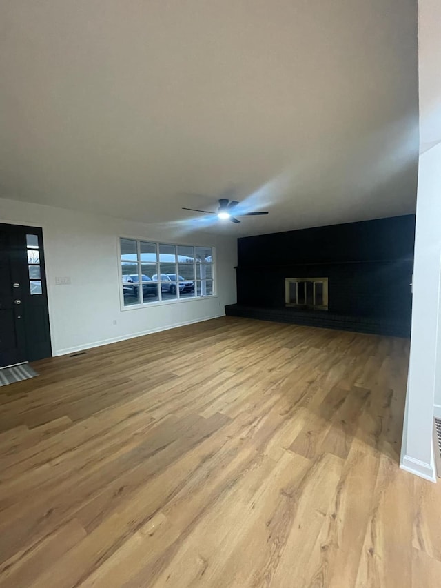 unfurnished living room with light wood-type flooring, baseboards, and a ceiling fan